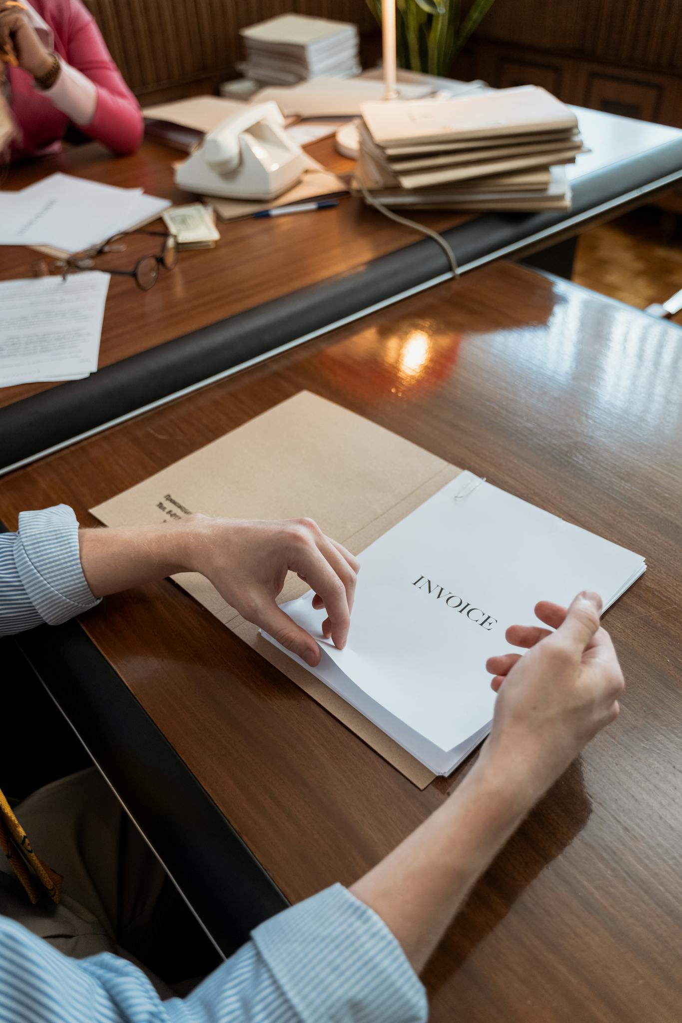 Hands sorting invoices on an office desk, showcasing administrative work indoors.