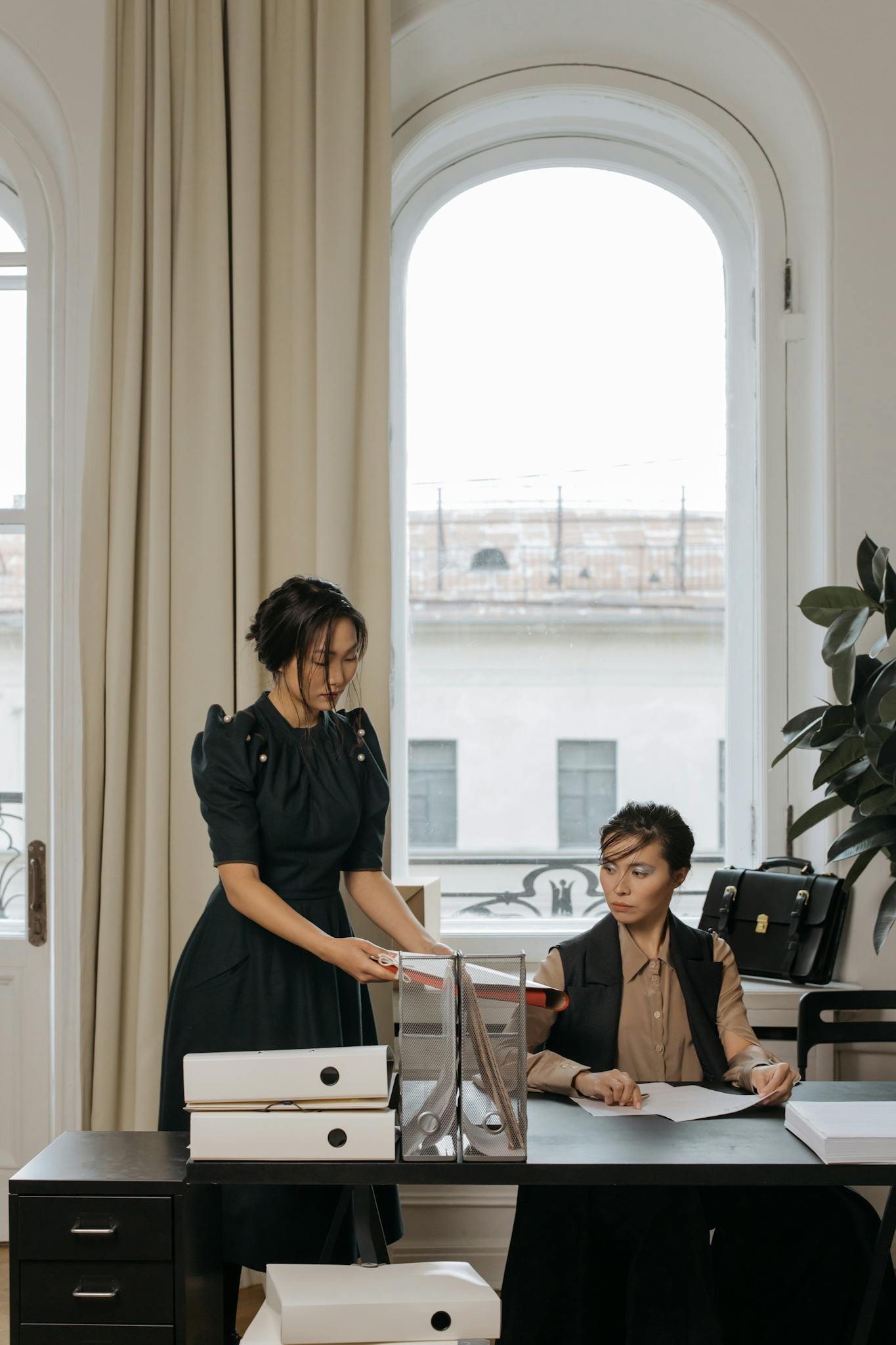 Two women working together with documents in a stylish office setting.
